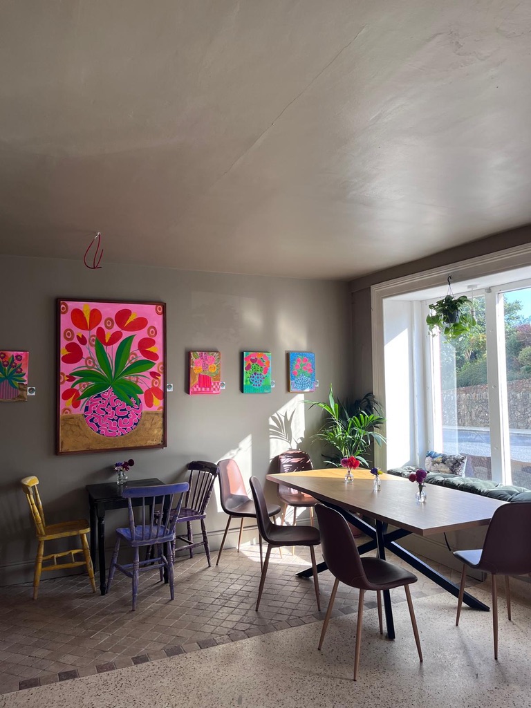 The warm, colourful interior of Cupán C with local artwork and tables in the sunshine